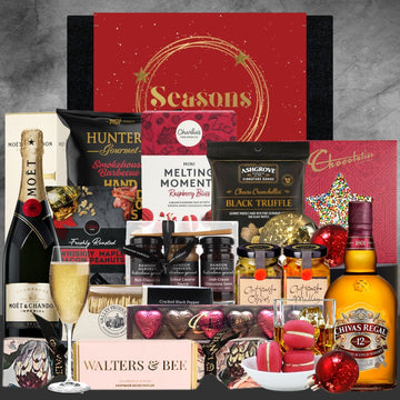 Gourmet gift basket with wine, chocolates, and snacks on a gray background