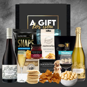Gift basket with wine, snacks, and other items on a gray background