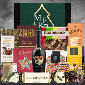 Assorted gift items including chocolate, snacks, and a bottle of Baileys on a textured surface.