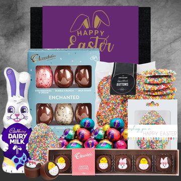 Assorted Easter treats including chocolate eggs, a bunny figurine, and cards on a gray background.