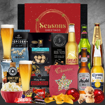 Christmas Gift basket with beer, snacks, and a card on a gray background