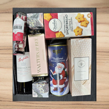 Christmas Gift box with wine, shortbread, and other items on a wooden surface