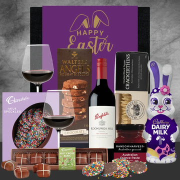 Gourmet Easter basket with wine, chocolate, and a bunny figure on a gray background