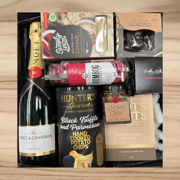 Gift box with Moet & Chandon champagne, glutin free Lavosh, dark chocolate almonds, raspberry humbug candy, black truffle potato chips, antipasto olives, roasted salted mixed nuts, and Christmas pudding