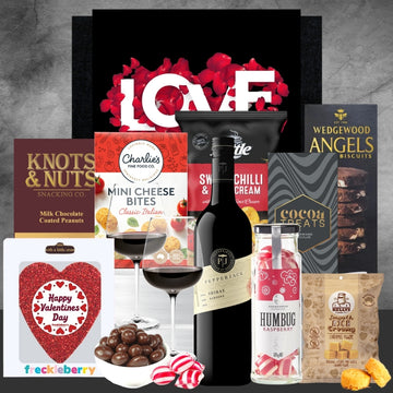 Gourmet gift set with wine, snacks, and confections on a gray background