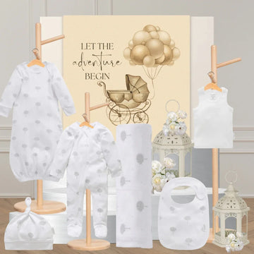 Baby clothing and accessories with a 'Let the adventure begin' sign in the background.