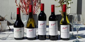 Penfolds wine bottles on a table with glasses outdoors