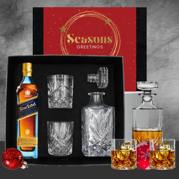 Whiskey gift set with Blue Label bottle, glasses, and decanter on a gray background.