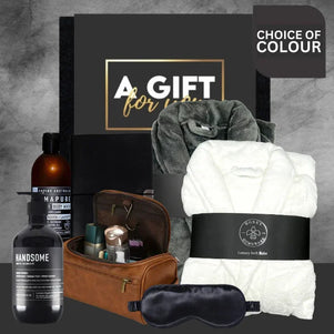 Gifting set with bath products, towel, and sleep mask on a gray background