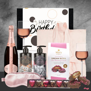 Gift set with champagne, bath products, and chocolates on a gray background