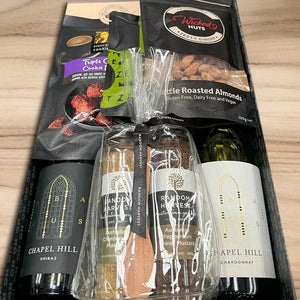 Wine gift set with Chapel Hill wines, crackers, and nuts on a wooden surface
