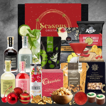 Assorted holiday-themed products including mini bottles, snacks, and a 'Seasons Greetings' card on a gray background.