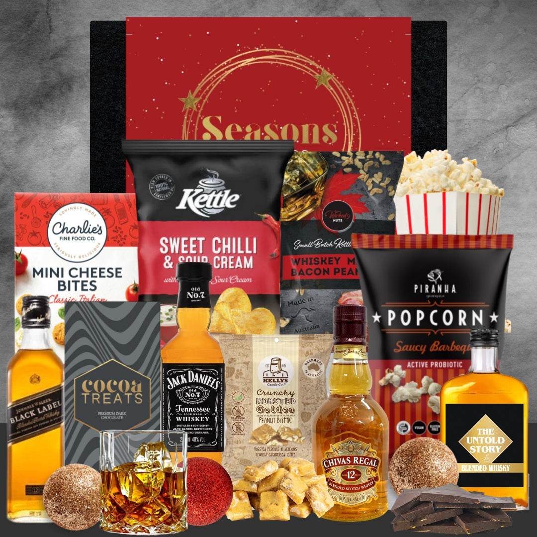 Holiday gift box with whiskey bottles, kettle chips, popcorn, mini cheese bites, peanut brittle, and dark chocolate