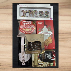Christmas gift box with sprinkles XMAS chocolate, cheese snacks, gingerbread cookies, chocolate almonds, crackers, and Chandon Rosé wine