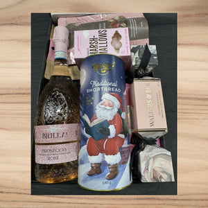 Christmas Gift basket with Prosecco, shortbread, and other items on a wooden surface