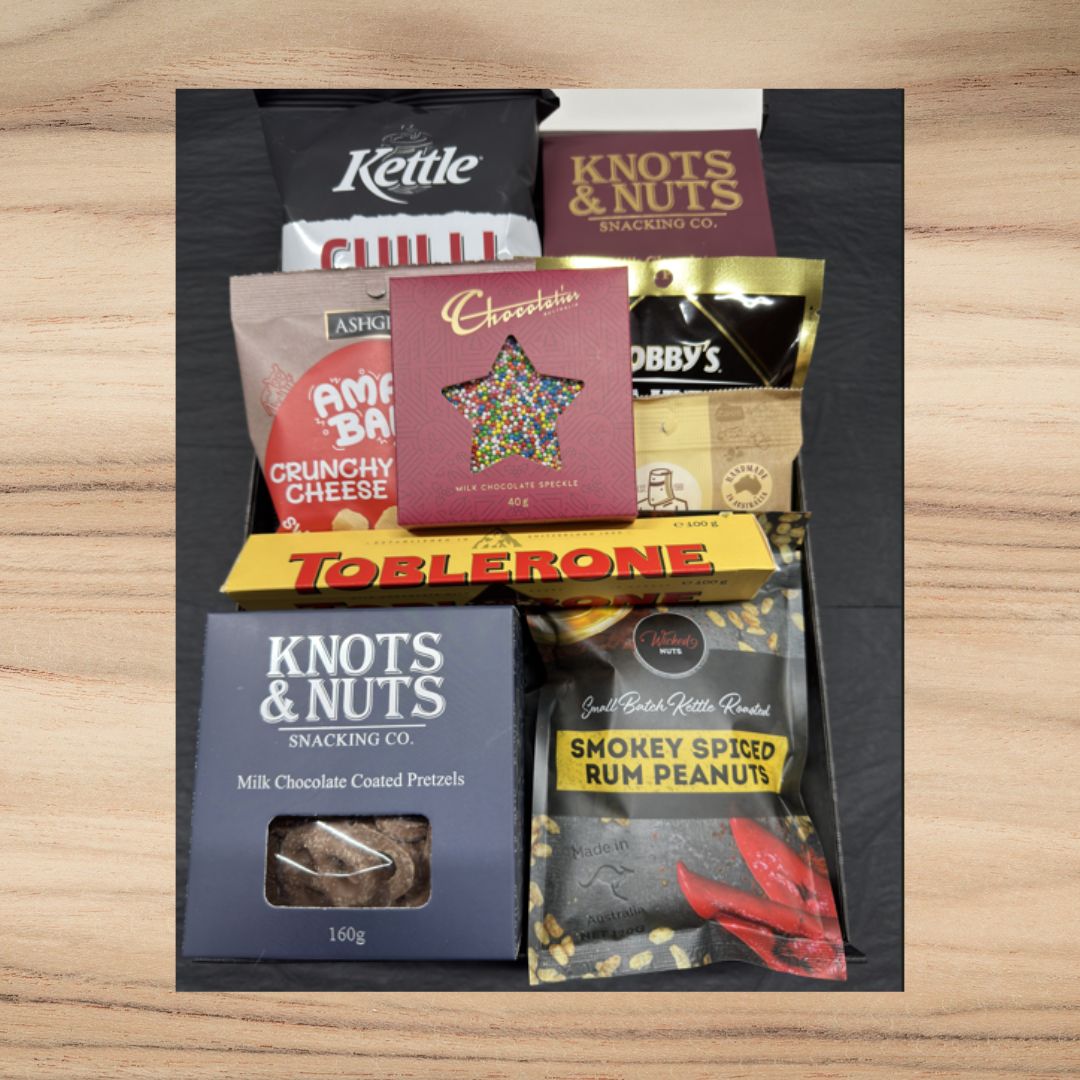 Variety gift box with Toblerone, smokey spiced rum peanuts, chocolate pretzels, crunchy cheese snacks, and colorful milk chocolate speckle