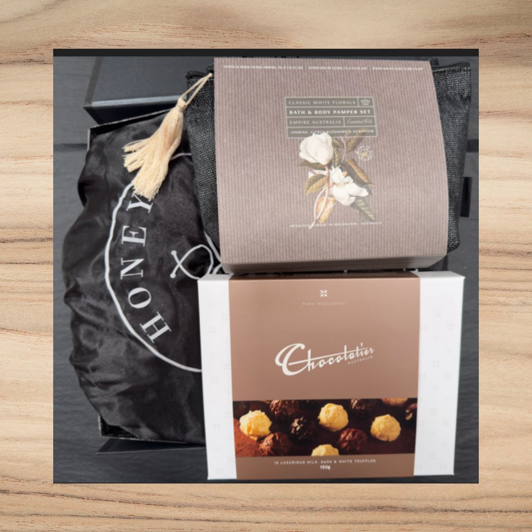 Gift hamper with Classic White Florals bath set and Chocolatier milk and dark truffles on wooden surface