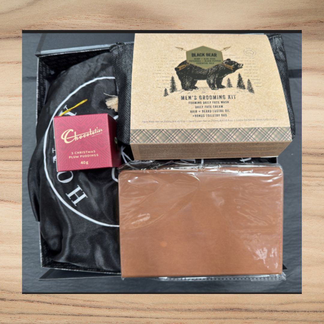 Gift box with Black Bear men's grooming kit, wrapped chocolate, and a brown toiletry bag