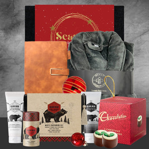 Holiday gift set with men's grooming kit, grey luxury bathrobe, red notebook, chocolates, and Christmas ornaments