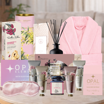Collection of self-care products including a robe, candles, and skincare items on a table.