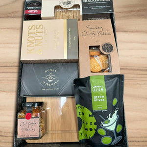 Assorted food items including crackers, cheese, and olives on a wooden surface