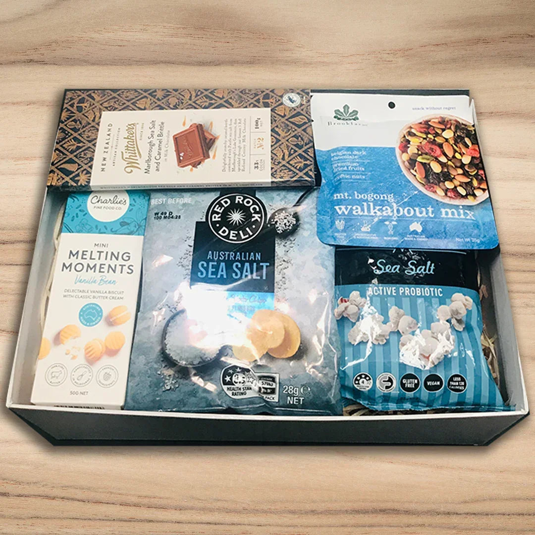 Assorted snack packages in a box on a wooden surface