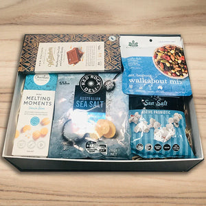 Assorted snack packages in a box on a wooden surface