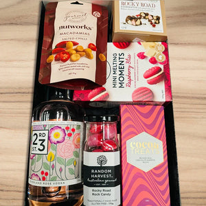 Assorted gourmet items including a bottle of vodka, candies, and cookies on a wooden surface.