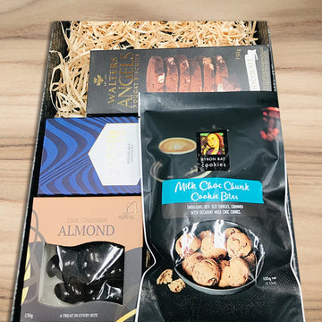 Gift basket with chocolate, cookies, and a book on a wooden surface