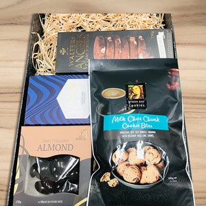 Gift basket with chocolate, cookies, and a book on a wooden surface