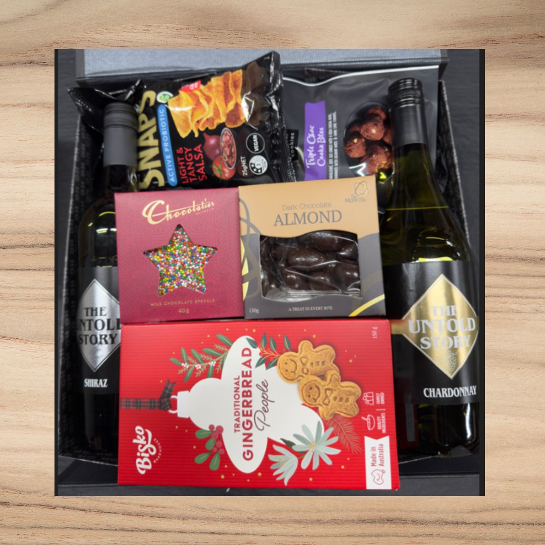 Christmas Gift set with wine, snacks, and a gingerbread people box on a wooden surface