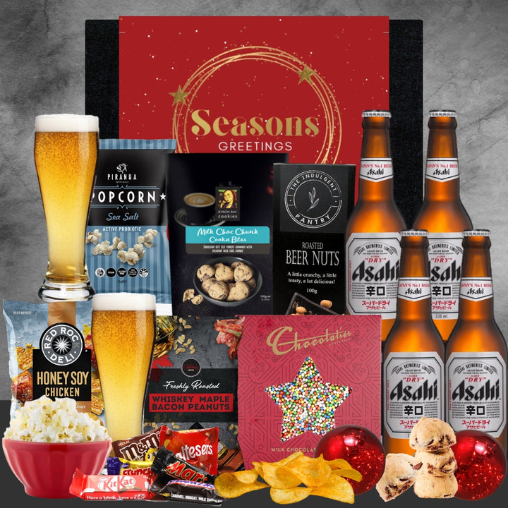 Christmas Gourmet gift set with beer, snacks, and a 'Seasons Greetings' card on a gray background.