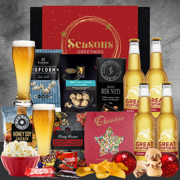 Christmas Gourmet gift set with beer, snacks, and a 'Seasons Greetings' card on a gray background.