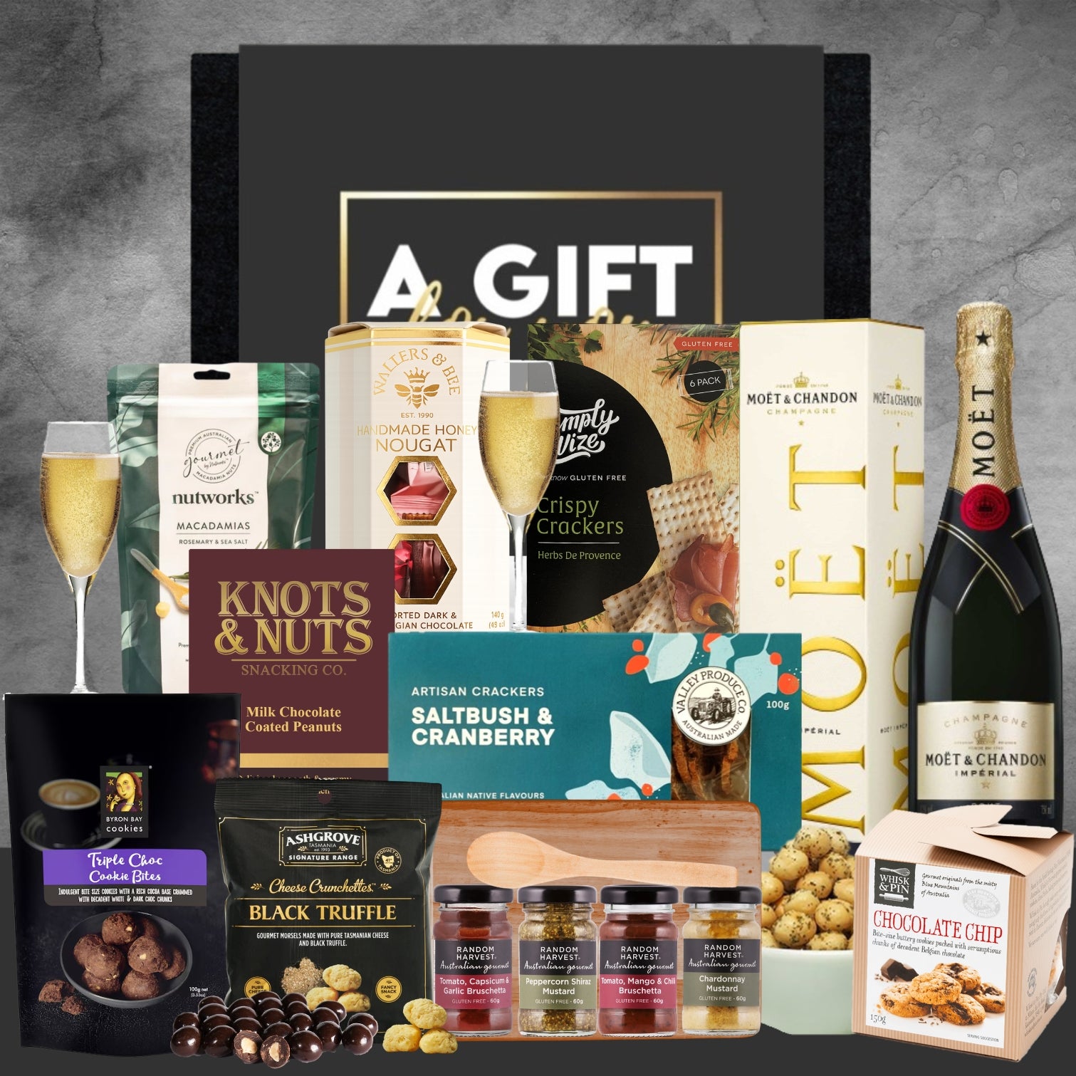 Gift basket with Moët & Chandon champagne, snacks, and truffles on a gray background