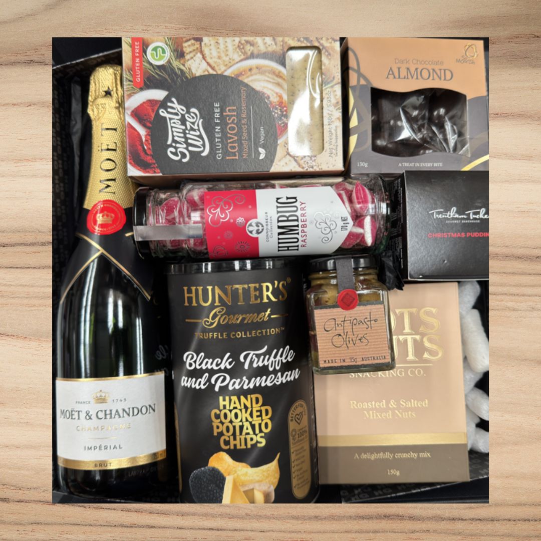 Gift box with Moet & Chandon champagne, glutin free Lavosh, dark chocolate almonds, raspberry humbug candy, black truffle potato chips, antipasto olives, roasted salted mixed nuts, and Christmas pudding