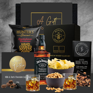 Gift set with Jack Daniel's whiskey, snacks, and a whiskey glass on a gray background