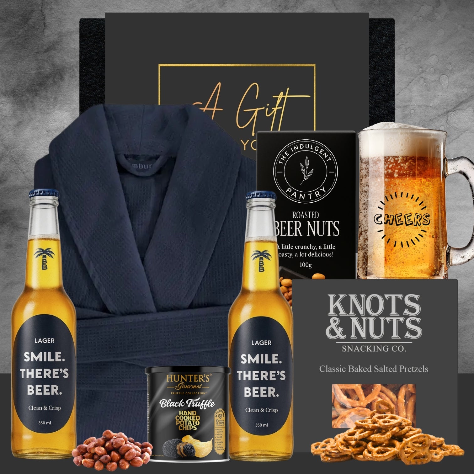 Gift set with beer bottles, snacks, and a robe on a gray background
