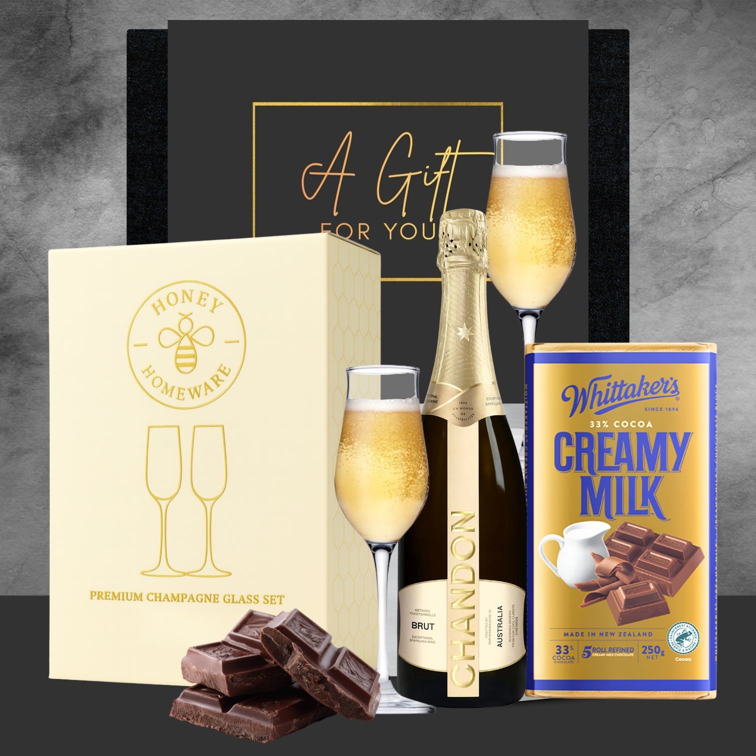 Gift set with champagne, chocolate, and a box of chocolates on a gray background