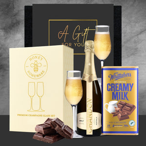 Gift set with champagne, chocolate, and a box of chocolates on a gray background