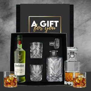 Whiskey gift set with Glenfiddich bottle, glasses, and decanter on a dark background.