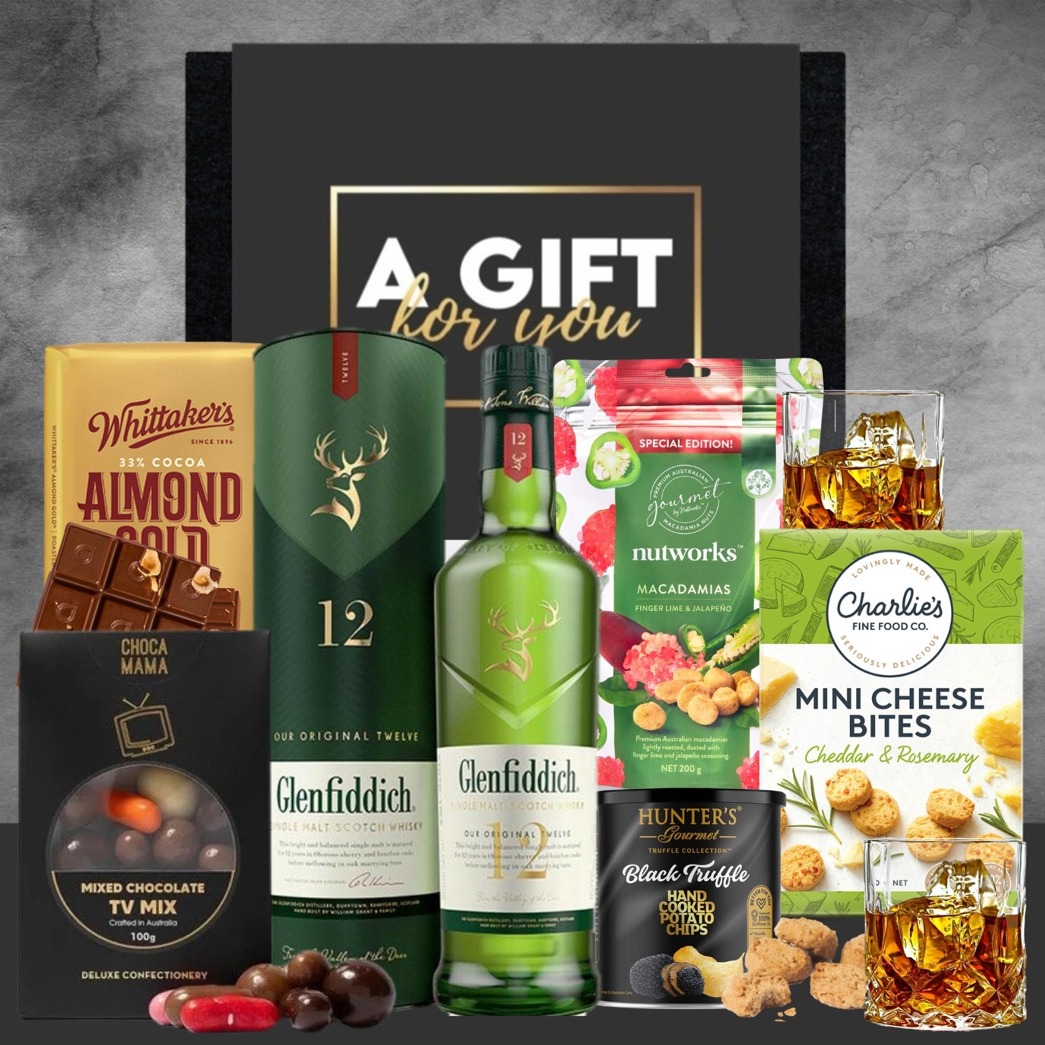Glenfiddich 12 whisky gift set with snacks and chocolates on a gray background