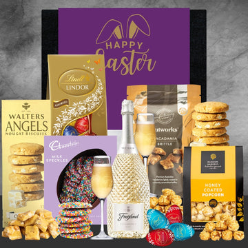 Gourmet Easter basket with chocolate, cookies, and champagne on a gray background