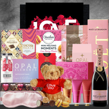 Gourmet gift basket with teddy bear, chocolate, and Moet & Chandon champagne on a dark background.