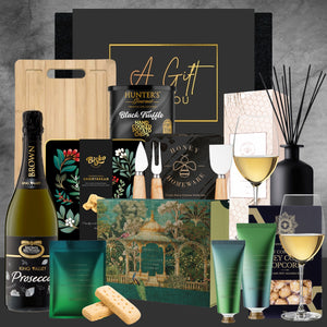 Gourmet gift basket with wine, truffles, and other items on a dark background
