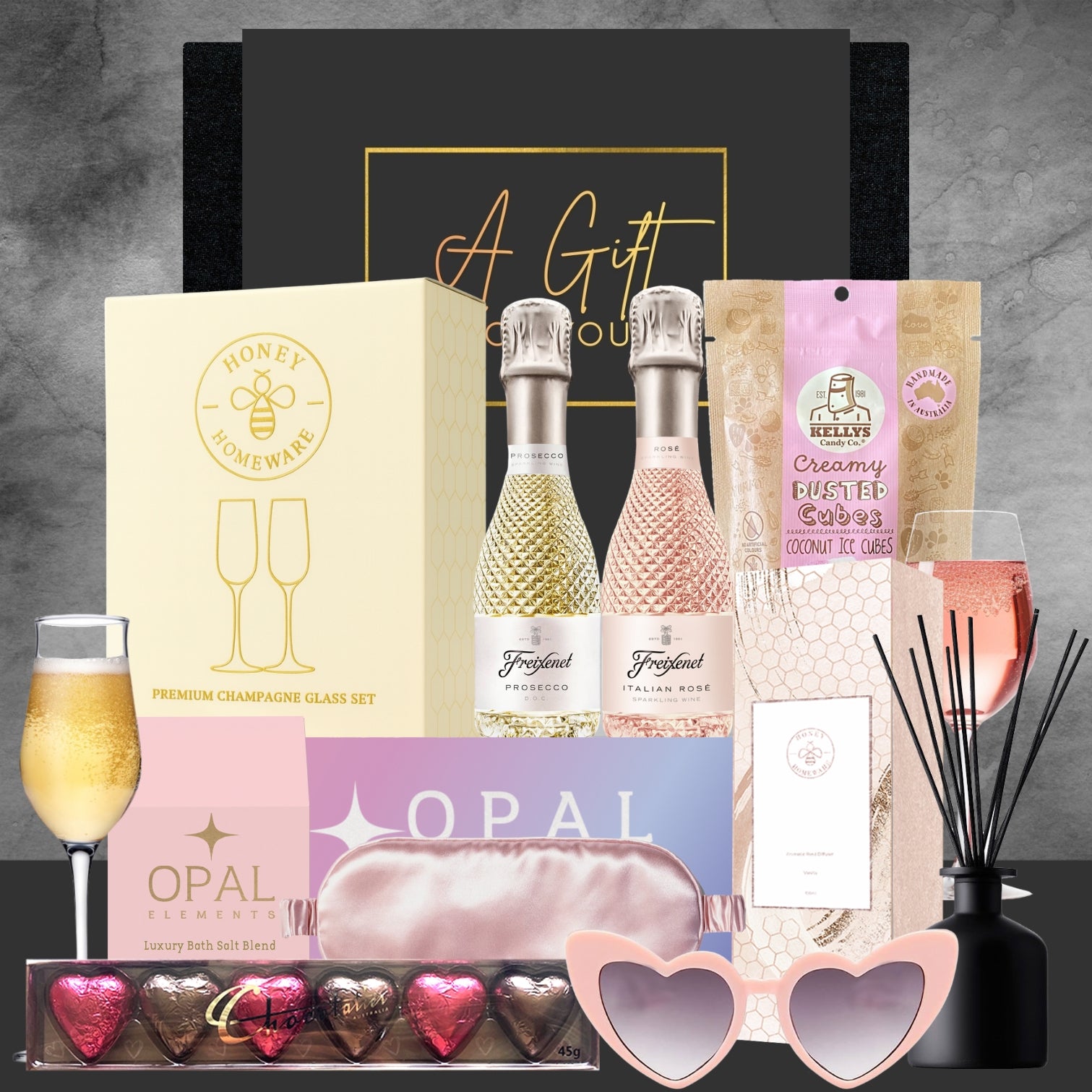 Gourmet gift set with champagne, chocolates, and other items on a gray background