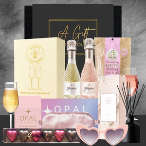 Gourmet gift set with champagne, chocolates, and other items on a gray background