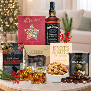 Gourmet gift set with Jack Daniel's whiskey, snacks, and chocolates on a table.