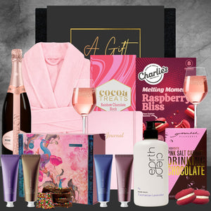 Gourmet gift set with champagne, chocolate, and bath products on a gray background