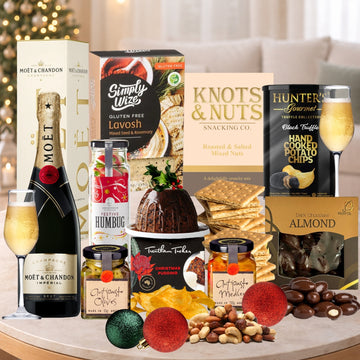 Gourmet gift set with champagne, snacks, and treats on a table.