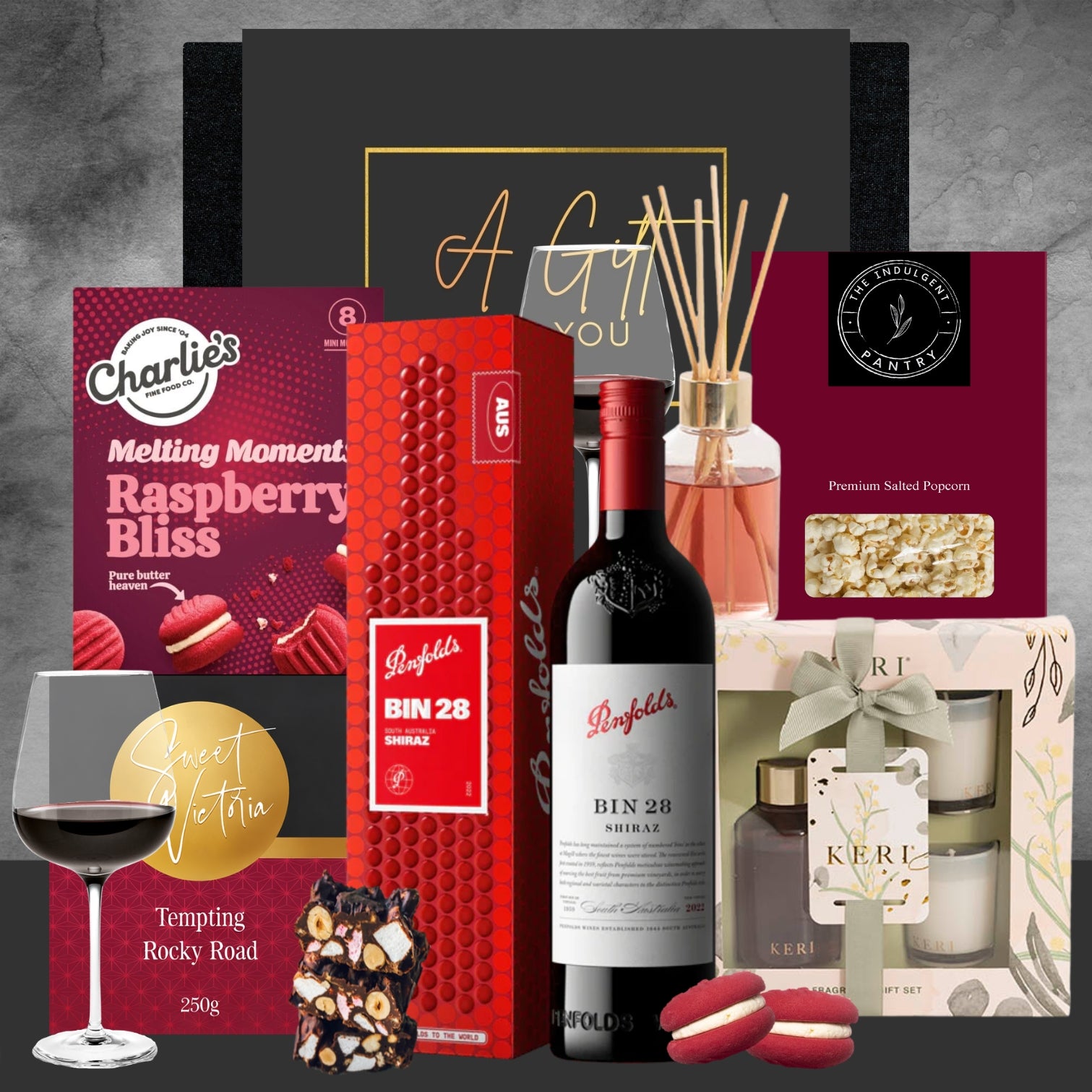 Gourmet gift set with wine, chocolate, and other items on a gray background